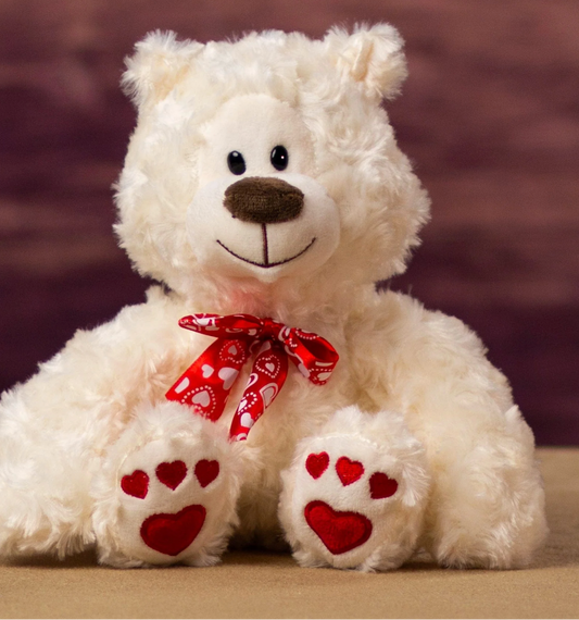 White teddy bear with red heart paws and a bow