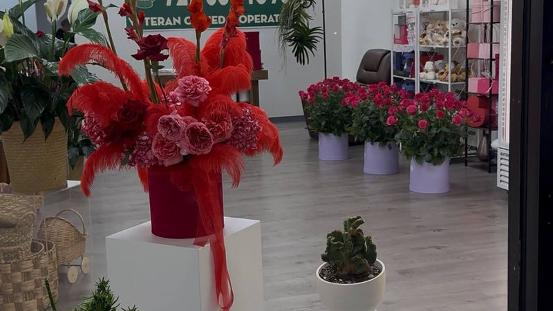 A flower shop interior with red floral arrangements and pink potted plants.