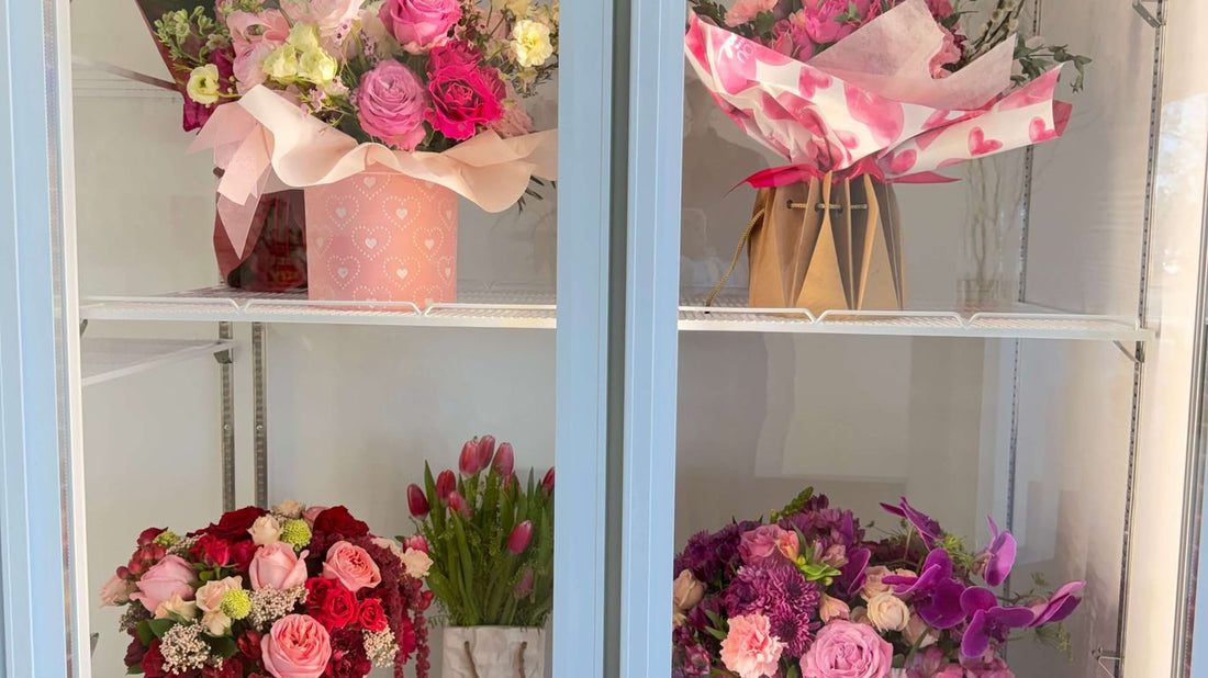 Four shelves display various bouquets of fresh flowers in a cooler.