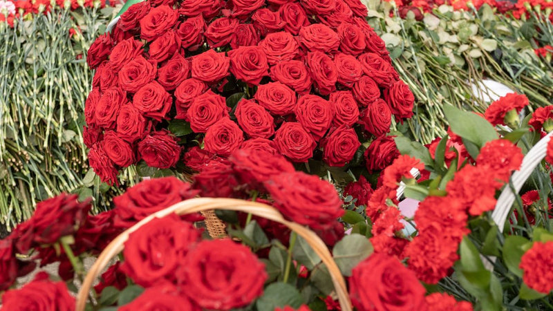 A large arrangement of red roses and carnations in baskets.