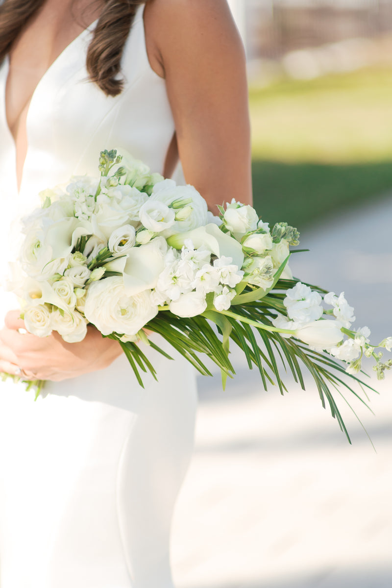 A person holds a beautiful bouquet of white flowers and greenery, perfect for expressing sympathy.