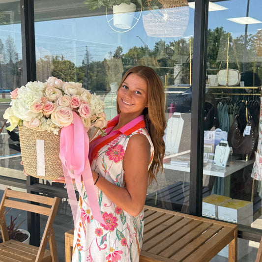 Woman holding a large floral arrangement in front of a store window