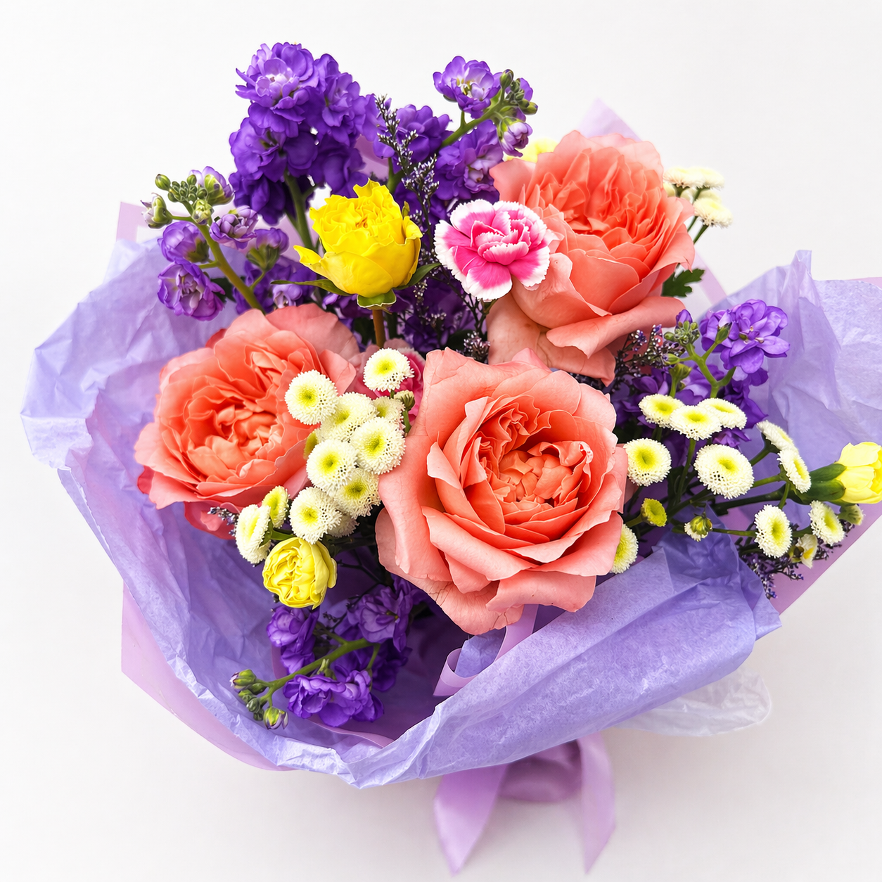 Bouquet of colorful flowers wrapped in purple paper on a white background