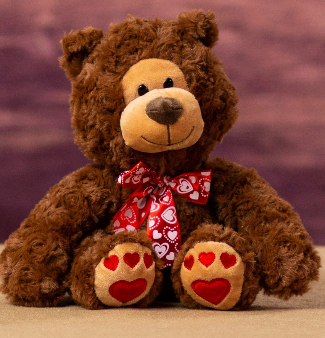 Brown teddy bear with a red bow and heart paws 