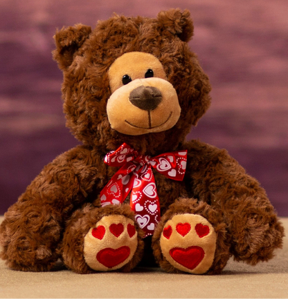 Brown teddy bear with a red bow and heart paws 