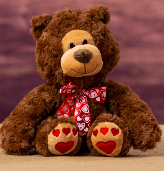 Brown teddy bear with a red bow and heart paws 