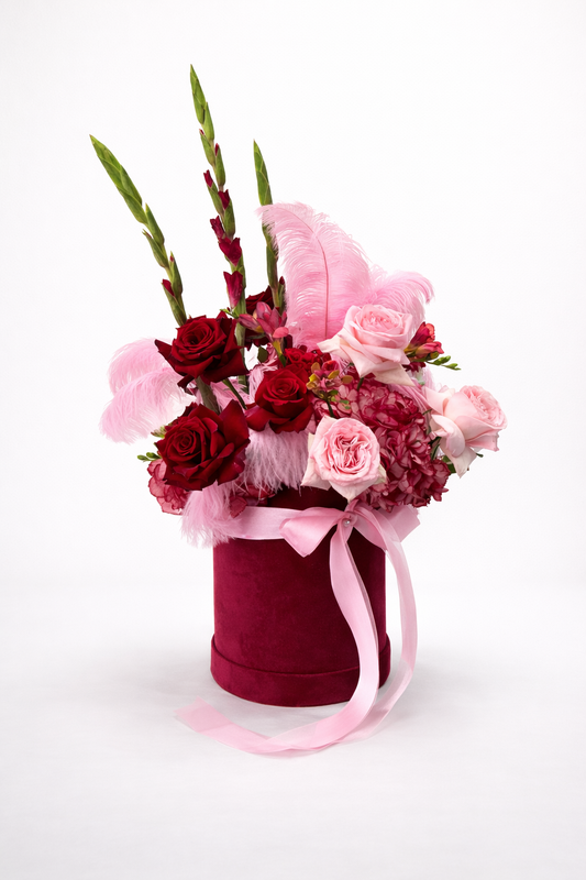 Floral arrangement in a red box with pink ribbon 