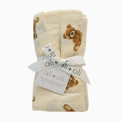 Folded baby blanket with teddy bear pattern and ali+oli tag on a white background