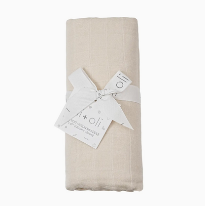 Folded beige muslin swaddle with a white tag on a white background