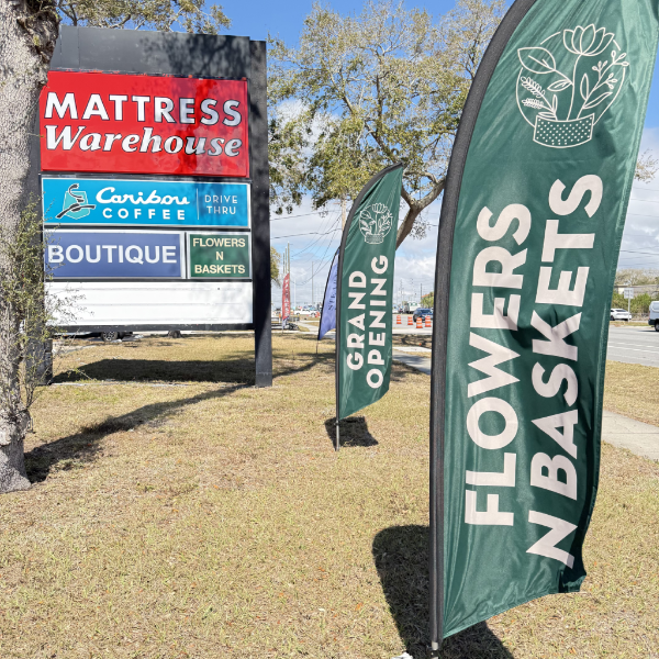 Outdoor scene with various signs including 'Mattress Warehouse' and 'Flowers N Baskets' flags.