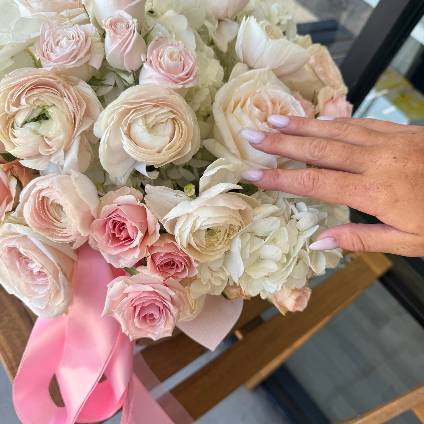 Bouquet of pink and white flowers with a hand touching it