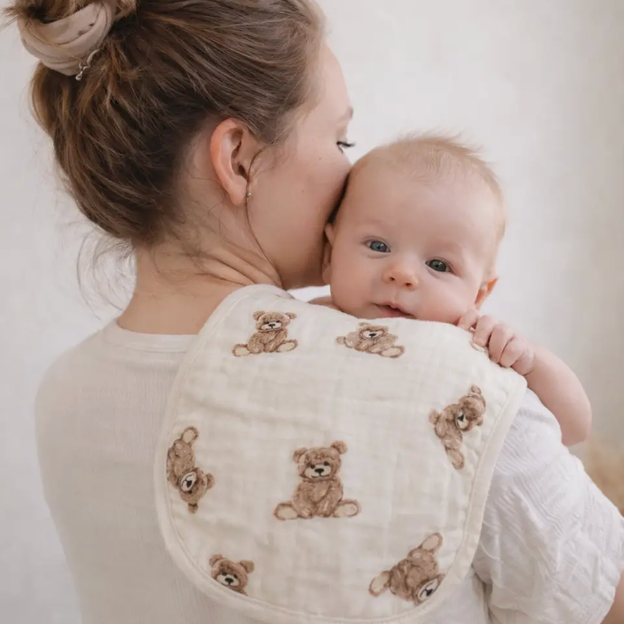 Woman holding a baby wrapped in a blanket with teddy bear patterns