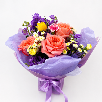Bouquet of flowers wrapped in purple paper with a white background