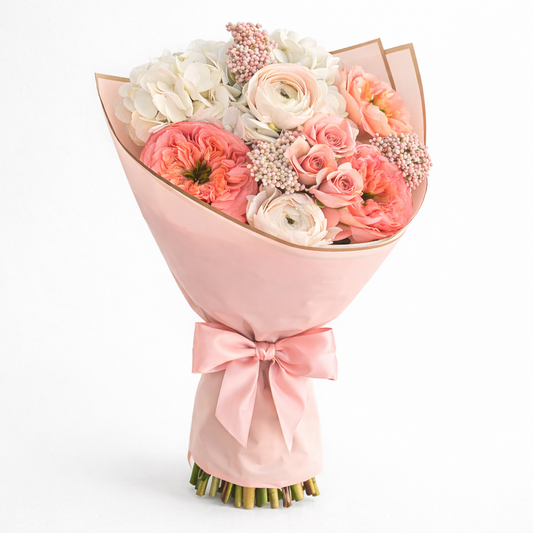 Bouquet of pink and white flowers wrapped in pink paper with a bow 