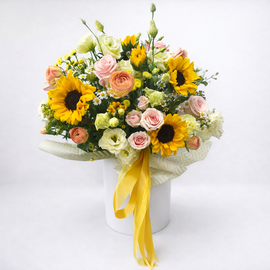 Bouquet of flowers with sunflowers and pink roses in a white box on a white background