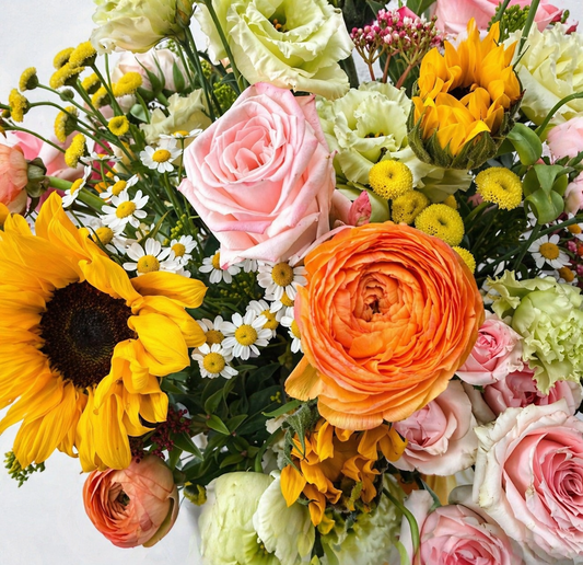 Bouquet of colorful flowers including sunflowers, roses, and ranunculus on a light background